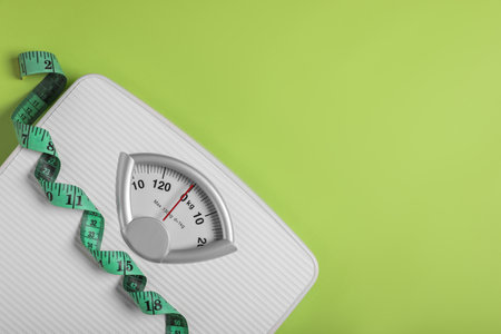 weight loss concept. Scales and measuring tape on green background, top view. Space for textの写真素材