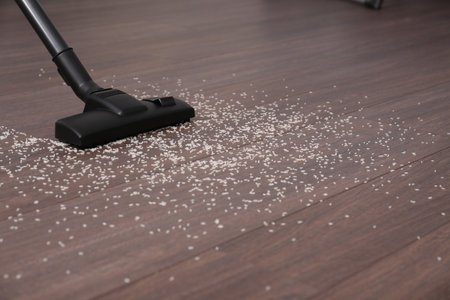Vacuuming scattered rice from wooden floor. Space for textの写真素材