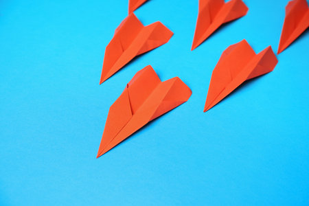 Many red paper planes on light blue background, above view