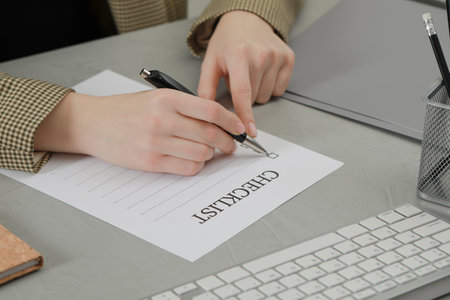 Woman filling Checklist at light gray table, closeupの写真素材