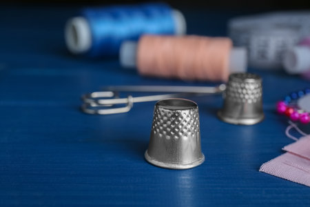 Silver timble on blue wooden table, space for text. Sewing accessoryの写真素材