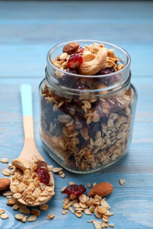 Jar of tasty granola with nuts and dry fruits on light blue wooden tableの写真素材