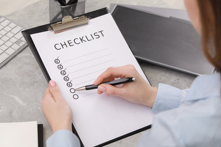Woman filling Checklist at gray marble table, closeupの写真素材