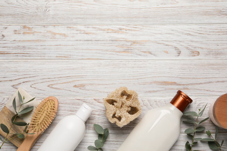 Shampoo bottles, loofah, hair brush and leaves on white wooden table, flat lay. Space for textの写真素材