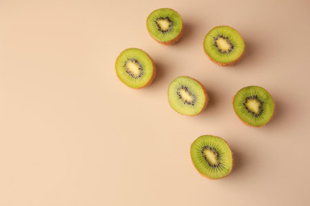 Halves of fresh kiwis on beige background, flat lay. Space for textの写真素材