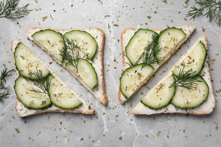 Tasty sandwiches with cream cheese, cucumber and dill on gray marble table, flat layの写真素材
