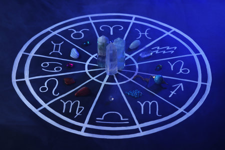 Natural stones for zodiac signs and drawn astrology chart on dark blue backgroundの写真素材