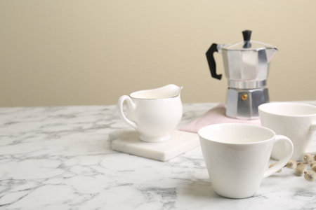 Cups, moka pot and jug on white marble table. Space for textの写真素材