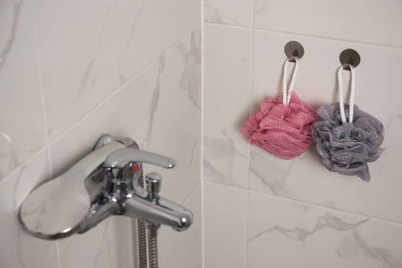 Shower puffs hanging near faucet in bathroom, space for textの写真素材