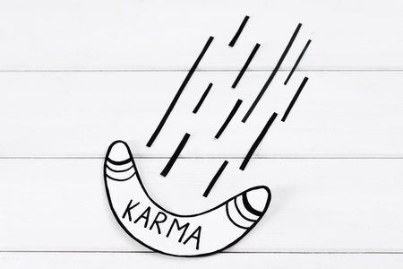 Paper boomerang with word Karma on white wooden table, flat layの写真素材