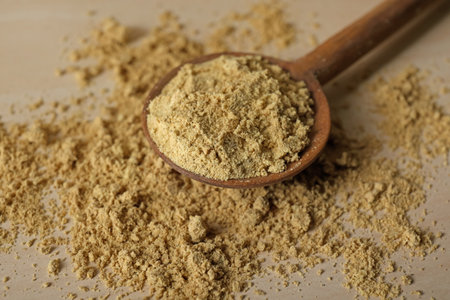 Spoon with aromatic mustard powder on wooden table, closeupの写真素材