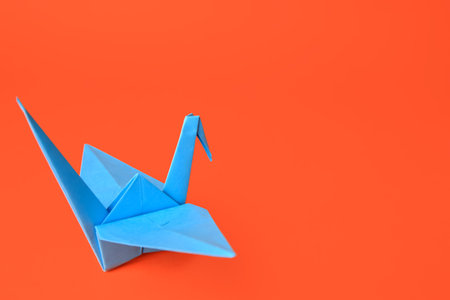 origami art. Handmade paper crane on orange background, space for textの写真素材