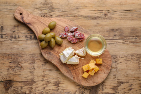 Toothpick appetizers. Pieces of sausage, cheese and honey on wooden table, top viewの写真素材