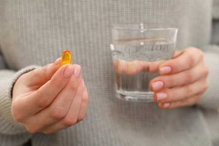 Woman holding glass of water and pill, closeup viewの写真素材