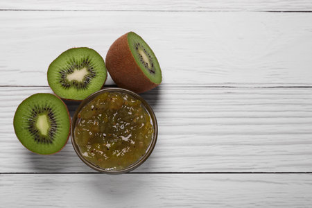 Jar with delicious kiwi jam and fresh fruits on white wooden table, flat lay. Space for textの写真素材