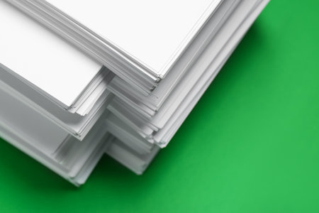 Stack of white paper on green background, closeup. space copy textの写真素材