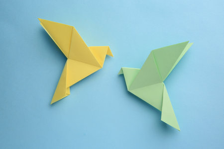 origami art. Colorful handmade paper birds on light blue background, flat layの写真素材