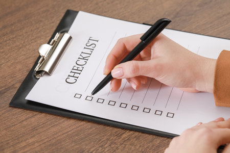 Woman filling Checklist at wooden table, closeupの写真素材
