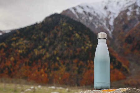 Thermo bottle on rock in mountains. Space for textの写真素材