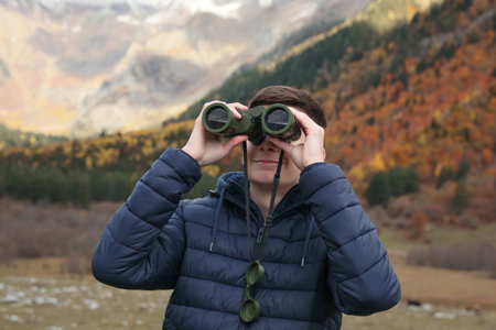 Boy looking through binoculars in beautiful mountainsの写真素材