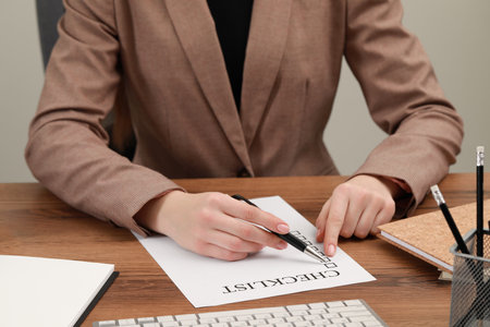 Woman filling Checklist at wooden table, closeupの写真素材