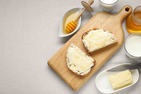 Slices of bread with butter, honey and milk on white table, flat lay. Space for textの写真素材