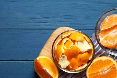 Orange peels preparing for drying and fresh fruits on blue wooden table, flat lay. Space for textの写真素材