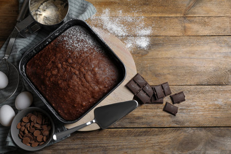 Homemade chocolate sponge cake and ingredients on wooden table, flat lay. Space for textの写真素材