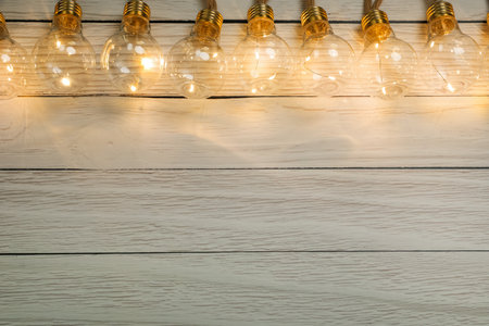 String lights with lamp bulbs on wooden background, top view. Space for textの写真素材