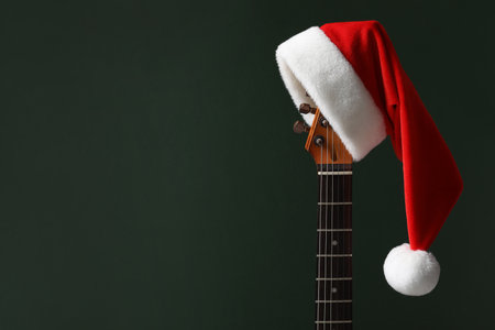 Guitar with Santa hat on green background, space for textの写真素材