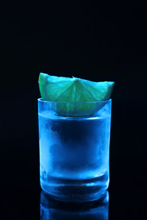 Shot glass of vodka with lime slice on dark backgroundの写真素材