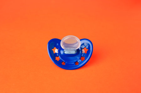 One blue baby pacifier on orange backgroundの写真素材