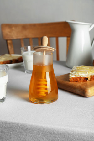 Delicious honey, milk and bread with butter served for breakfast on table indoorsの写真素材