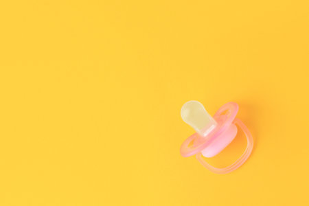 One new baby pacifier on orange background, top view. Space for textの写真素材