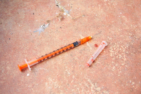 Disposable syringe with needle on red tiled surfaceの写真素材