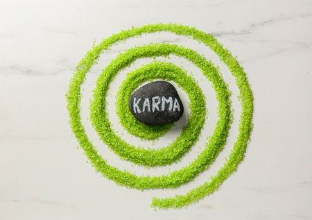 Stone with word Karma and circle made of light green sea salt on white marble table, top viewの写真素材