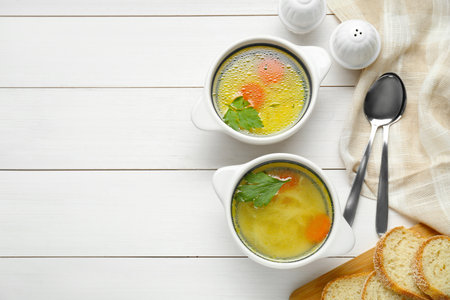 Delicious bouillon served on white wooden table, flat lay. Space for textの写真素材