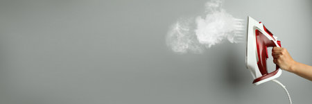 Woman with iron on light gray background, closeup. Banner design with space for textの写真素材