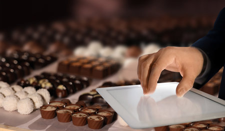 Production line of chocolate candies. Man working with tablet, closeupの写真素材