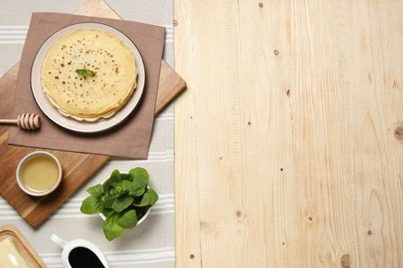Delicious crepes with mint and honey on wooden table, flat lay. Space for textの写真素材