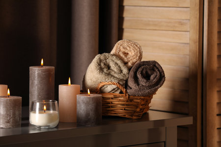 Spa composition with burning candles and rolled towels on table in wellness centerの写真素材