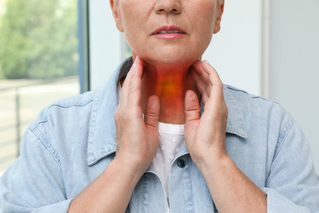 endocrine system. Mature woman doing thyroid self examination indoorsの写真素材