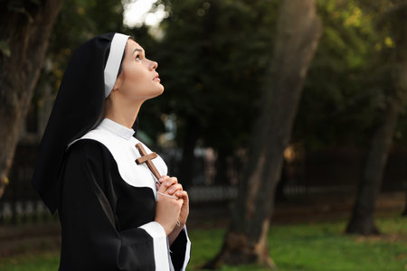 Young nun with Christian cross in park outdoors, space for textの写真素材
