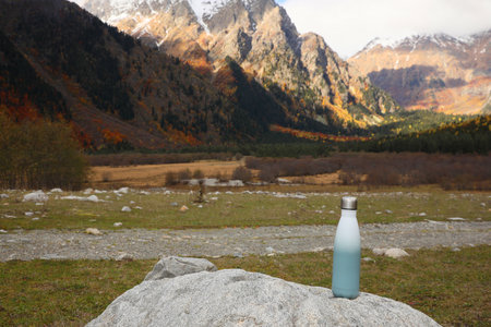Thermo bottle on rock in mountains. Space for textの写真素材