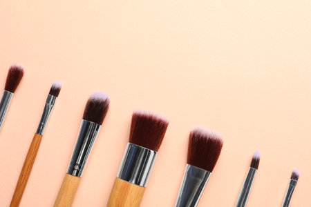 Set of makeup brushes on beige background, flat lay. Space for text