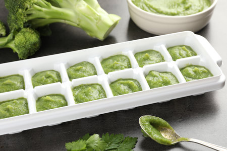 Broccoli puree in ice cube tray and ingredients on gray table, closeup. Ready for freezingの写真素材