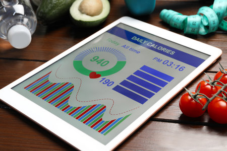 Tablet with weight loss calculator application and different products on wooden tableの写真素材