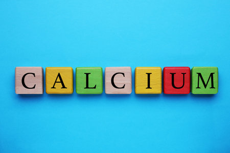 Word Calcium made of colorful wooden cubes with letters on light blue background, flat layの写真素材