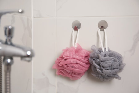 Shower puffs hanging near faucet in bathroomの写真素材