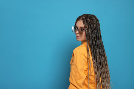 Beautiful woman with long african braids and sunglasses on blue background, space for textの写真素材